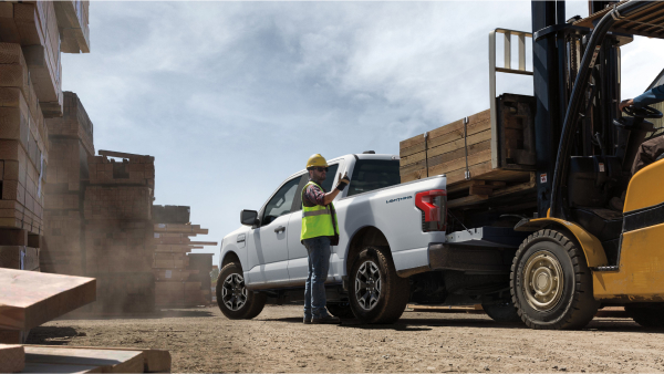 A construction worker overseeing the loading of a Ford F-150 Lightning® Pro on a worksite.
